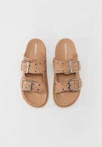 Sandali scivolati marroni con due cinturini larghi, fibbie argentate e dettagli borchiati. Materiale simile alla pelle liscio con suola piatta.