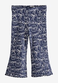Pantaloni blu a coste con un motivo di fiocchi bianchi, caratterizzati da orli svasati e un bordo arricciato. Vita elastica per il massimo comfort.