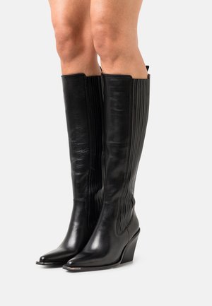 Botas de cuero negro hasta la rodilla con una forma elegante, punteras afiladas, detalle acanalado en la parte trasera y diseño de tacón cuña.