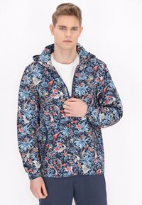 Giacca navy a fantasia floreale realizzata in materiale leggero, dotata di cappuccio, chiusura con zip e vivaci disegni di piante e uccelli rossi e blu.