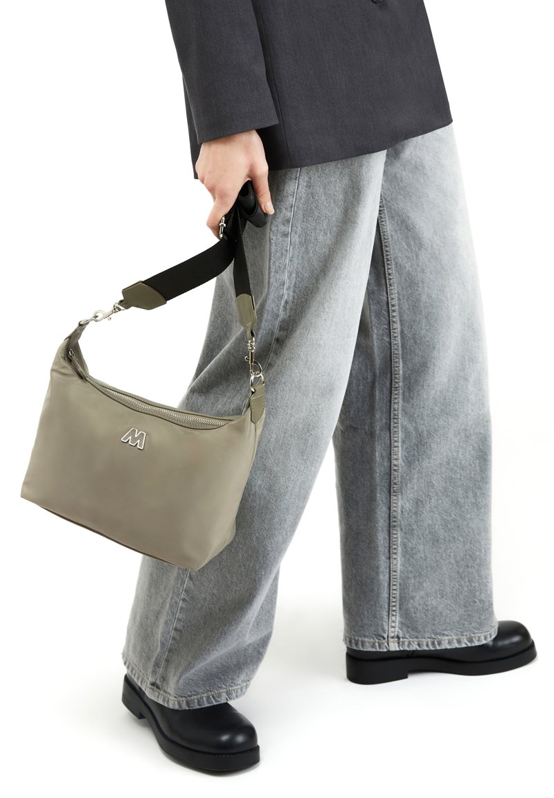 Maslinasto zeleni, mekani ramenski torba s zatvaranjem na zip; sadrži crni remen i srebrne detalje; pravokutnog je oblika s utisnutim logotipom.