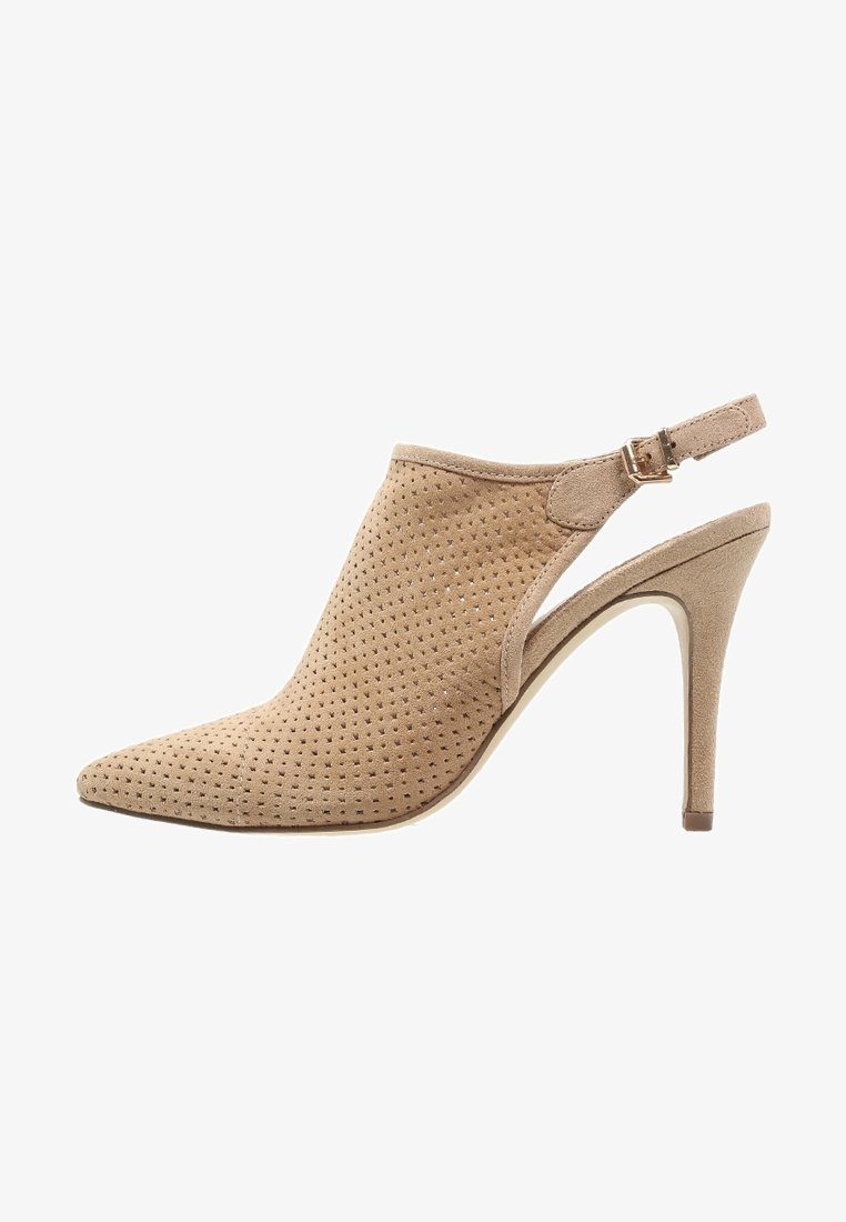 Chaussure à talons hauts en daim perforé beige, à bout pointu et bride de cheville réglable, avec un élégant talon aiguille.