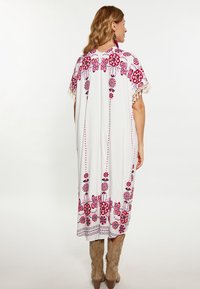 Weißes Kaftan mit bunter Blumenstickerei in Rot und Blau, verziert mit Fransenakzenten an den Ärmeln und dem unteren Saum.