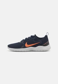 Chaussures de course Nike avec un dessus en maille bleu marine et un logo orange, dotées d'une semelle blanche flexible et de détails texturés sur les côtés.