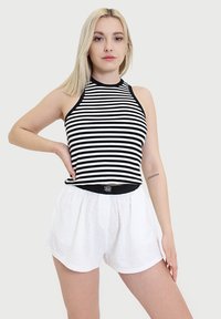 Czarnobiała, paskowana, bezrękawnik połączona z białymi, lekkimi szortami na gumce. Prosta, codzienna letnia stylizacja.