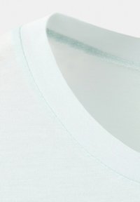 Gros plan sur un tissu bleu clair à col rond montrant une texture tricotée fine et des coutures intérieures du col.