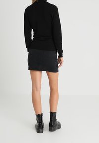 Svart polotröja i kombination med en svart denimkjol och svarta ankelboots. Outfiten har en figursydd design och en mjuk textur.