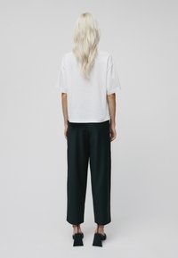 Camiseta blanca de manga corta con un ajuste relajado, combinada con pantalones negros de cintura alta con pierna ancha y largo recortado.