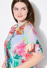 Vestido con un estampado floral colorido y mangas cortas con volantes. Presenta un frente con botones y una paleta de colores variada que incluye rosa, verde y azul.