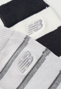 Dos pares de calcetines, uno en azul marino oscuro con gruesas costillas, el otro en gris claro con rayas verticales; ambos presentan un logo bordado.