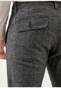 Wełniane spodnie w szare, czarne i czerwone kratę houndstooth, z guzikową kieszenią z tyłu i gładkim, teksturowanym wykończeniem.