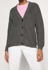 Dark gray knitted cardigan with a deep V-neck, five black buttons, ribbed texture, and long sleeves, worn over a light pink shirt.