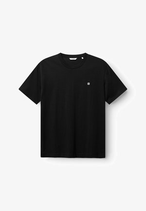 Camiseta negra de manga corta con cuello redondo y un pequeño logo cuadrado blanco en el pecho izquierdo sobre un fondo blanco.