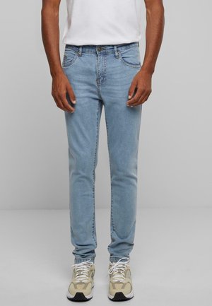 Lichtblauwe denim jeans met een slim fit, met vijf zakken, een knoopsluiting en lichte vervaging. Gecombineerd met beige sneakers.