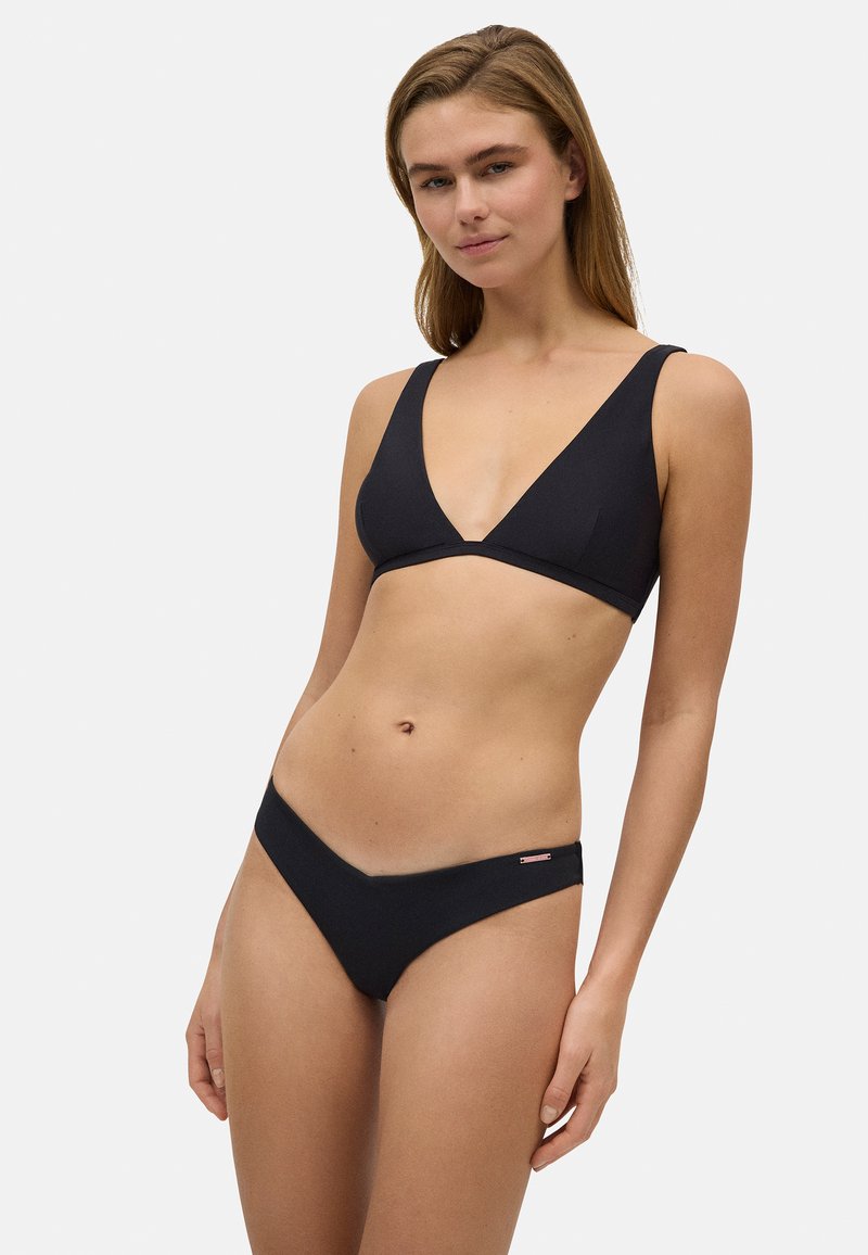 Conjunto de bikini negro que presenta un top con escote en V profundo y tirantes anchos, junto con braguitas de corte bajo. Está hecho de una tela suave con un detalle de marca mínimo.