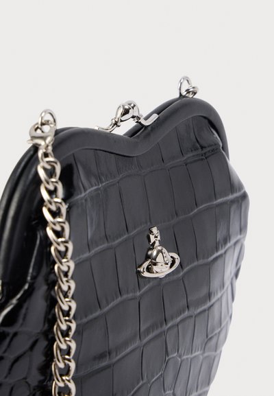 Μαύρη τσάντα χειρός με ανάγλυφο μοτίβο κροκόδειλου, καμπυλωτή κορυφή, ασημένια εξαρτήματα και λουρί αλυσίδα, με χαρακτηριστικό κλείσιμο μπροστά.