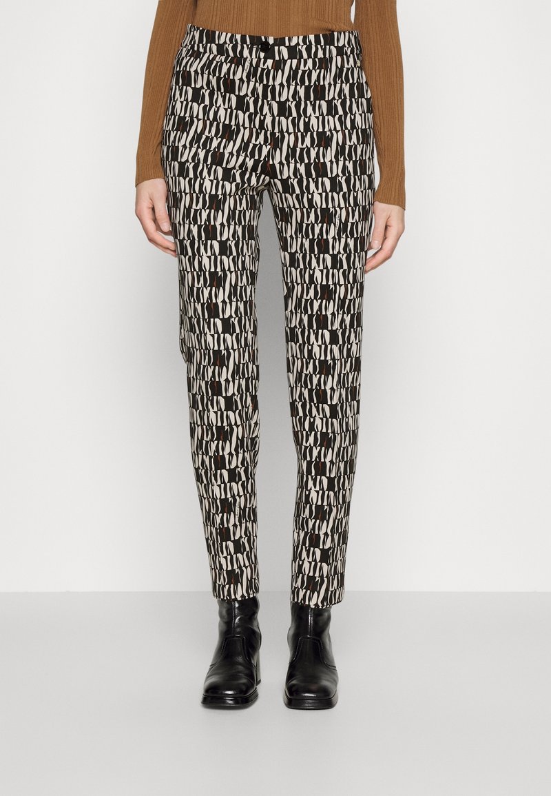 Zwart-witte gestreepte broek met een smal ontwerp. De stof is glad; heeft bruine accenten en een klassieke tailleband. Gedirigeerd met zwarte enkellaarsjes.