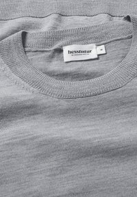 Grauer Strickpullover mit rundem Ausschnitt und glatter Textur. Das Etikett zeigt "hessnatur" mit der Größe "M".
