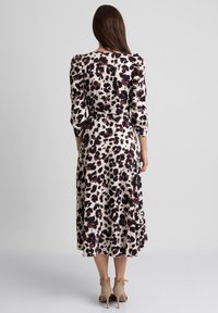 Midi sukienka z wzorzystej tkaniny z kremowym tłem, na którym znajdują się ciemno-brązowe i burgundowe plamy, z długimi rękawami i rozkloszowanym dołem.