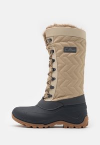 Botte imperméable beige avec un design matelassé, bordure en fourrure et semelle en caoutchouc foncé. Comprend un devant à lacets et des accents texturés pour une meilleure adhérence.