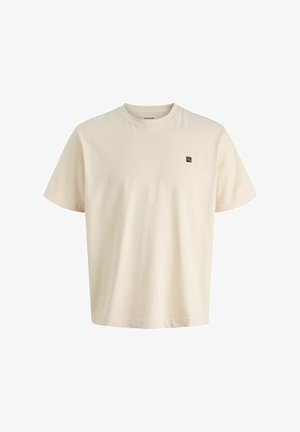 Beige puuvillane T-särk ümarate kaelustega ja lühikeste varrukatega; vasakul rinnal on väike must logo. Pehme tekstuur ja mugav lõige.