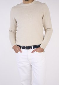 Beige gestrickter Pullover mit rundem Halsausschnitt, kombiniert mit weißen Jeans und einem dunkelblauen Ledergürtel. Einfaches und sauberes Design.