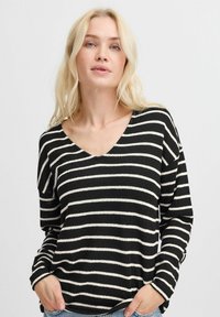 gestreifter Pullover in Schwarz und Weiß mit V-Ausschnitt, langen Ärmeln und lockerer Passform. Hergestellt aus einem strukturierten Strickstoff.