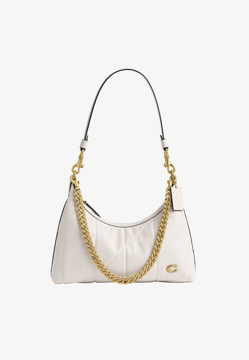 Sac à main en cuir blanc matelassé avec chaîne et fermoir dorés, bandoulière noire et petite étiquette rectangulaire en cuir attachée à la partie métallique.