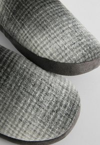 Grå og hvide sutsko uden hæl med et tekstureret ternet design og blødt stofoverdel. Gummisål for bedre greb og holdbarhed.