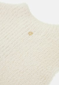 Maglione lavorato a maglia color crema con una texture soffice, caratterizzato da un sottile accento del logo dorato vicino al collo e un design del colletto rotondo.