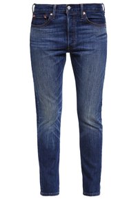 Tummansiniset farkut kapealla leikkauksella. Ominaisuuksiin kuuluu viisi taskua, vetoketjusauma ja kontrastiväriset saumarjätteet. Tasainen rakenne.