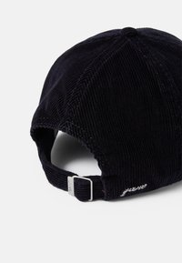 Cappellino da baseball in corduroy blu navy con visiera curvata, cinturino regolabile e dettaglio del logo ricamato sul retro. Texture morbida e motivo a coste distintivo.