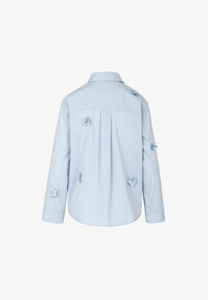Camicia azzurra a maniche lunghe con collo, caratterizzata da dettagli floreali in rilievo sul retro e da una piega centrale.