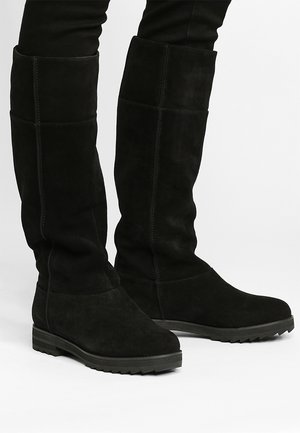 Zwarte suède kniehoge laarzen met een platte rubberen zool, gekenmerkt door een gladde textuur en eenvoudige stiksels, ontworpen voor een perfecte pasvorm.