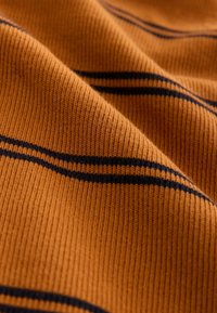 Narančasta rebrasta tkanina s crnim horizontalnim prugama, teksturirana za toplinu, prikazuje mek izgled s blagom rastezljivošću.
