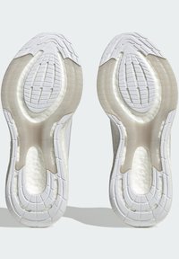 Witte sportieve schoenzolen met getextureerde grippatronen, met een glad, glanzend midden en verhoogde randen voor grip en ondersteuning.