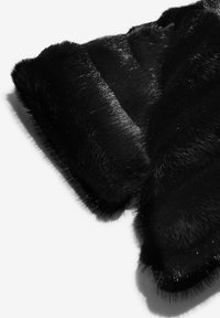 Melnas mākslīgās spalvas audums ar mīkstu, teksturētu virsmu. Tam ir spīdīga mirdzuma un pūkaini mali, radot bagātīgu, daudzslāņu izskatu.