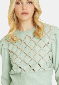 Maglione verde menta con motivo a diamante intagliato, impreziosito da strass. Presenta un orlo a coste e maniche a sbuffo.