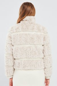 Crème kleurige nepbontjas met een gestructureerd gestreept patroon en een hoge kraag. Heeft een cropped snit en een zachte, luxe afwerking.