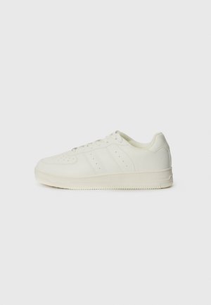 White sneakers with a smooth leather texture, lace-up design, perforated detailing, and three diagonal stripes on the side. Rubber sole.
