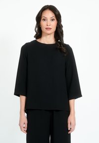 Maglietta nera a maniche corte con scollatura rotonda e vestibilità comoda. Realizzata in tessuto liscio con una sottile texture, presenta un orlo dritto.