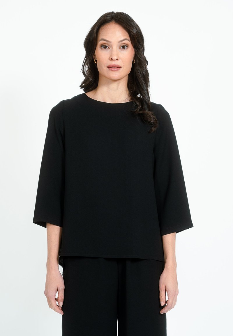 Maglietta nera a maniche corte con scollatura rotonda e vestibilità comoda. Realizzata in tessuto liscio con una sottile texture, presenta un orlo dritto.