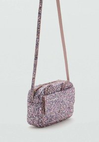 Piccola borsa a tracolla scintillante in toni di rosa e viola, con una lunga tracolla e compartimenti a doppia cerniera, posizionata su uno sfondo semplice.