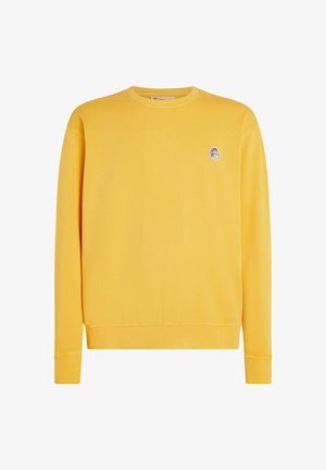 Geltona visų pavadinimų megztinis su ilgomis rankovėmis, apvalia iškirpte, raibomis rankogaliais ir apačia, su mažuoju apvaliu logotipu kairiajame krūtinės šone. Minkšta medvilnės medžiaga.