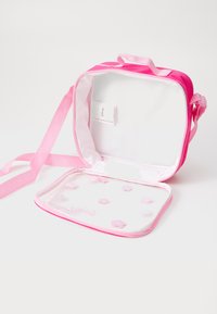 Roze draagtas met een doorzichtige voorkant, voorzien van een ritssluiting en kleine bloemenaccenten aan de binnenkant. Inclusief een band voor gemakkelijke draagbaarheid.