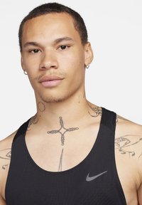 Schwarzes sportliches Tanktop aus leichtem Material mit einem runden Ausschnitt und einem kleinen grauen Nike-Logo auf der linken Brust.