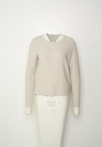 Pull beige côtelé à manches longues avec un col rond. Présente des accents blancs contrastants au col et aux poignets. Mélange de coton ou de laine.