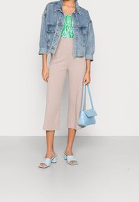 Denim jacket, green patterned top, beige ribbed cropped pants, blue block-heeled mules, and a light blue textured handbag.