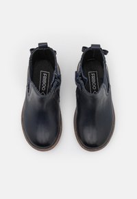 Bottines en cuir bleu marine, avec une finition lisse, des zippers latéraux et une doublure intérieure texturée. Semelles en caoutchouc avec une légère teinte brune.