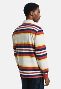 Langsleeve shirt met meerdere horizontale strepen in rood, geel, blauw en wit op een lichte achtergrond, met een klassiek kraagontwerp.